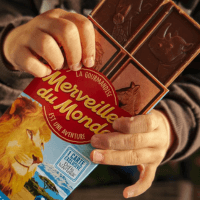 Mains d'enfant ouvrant une tablette de chocolat Merveilles du Monde