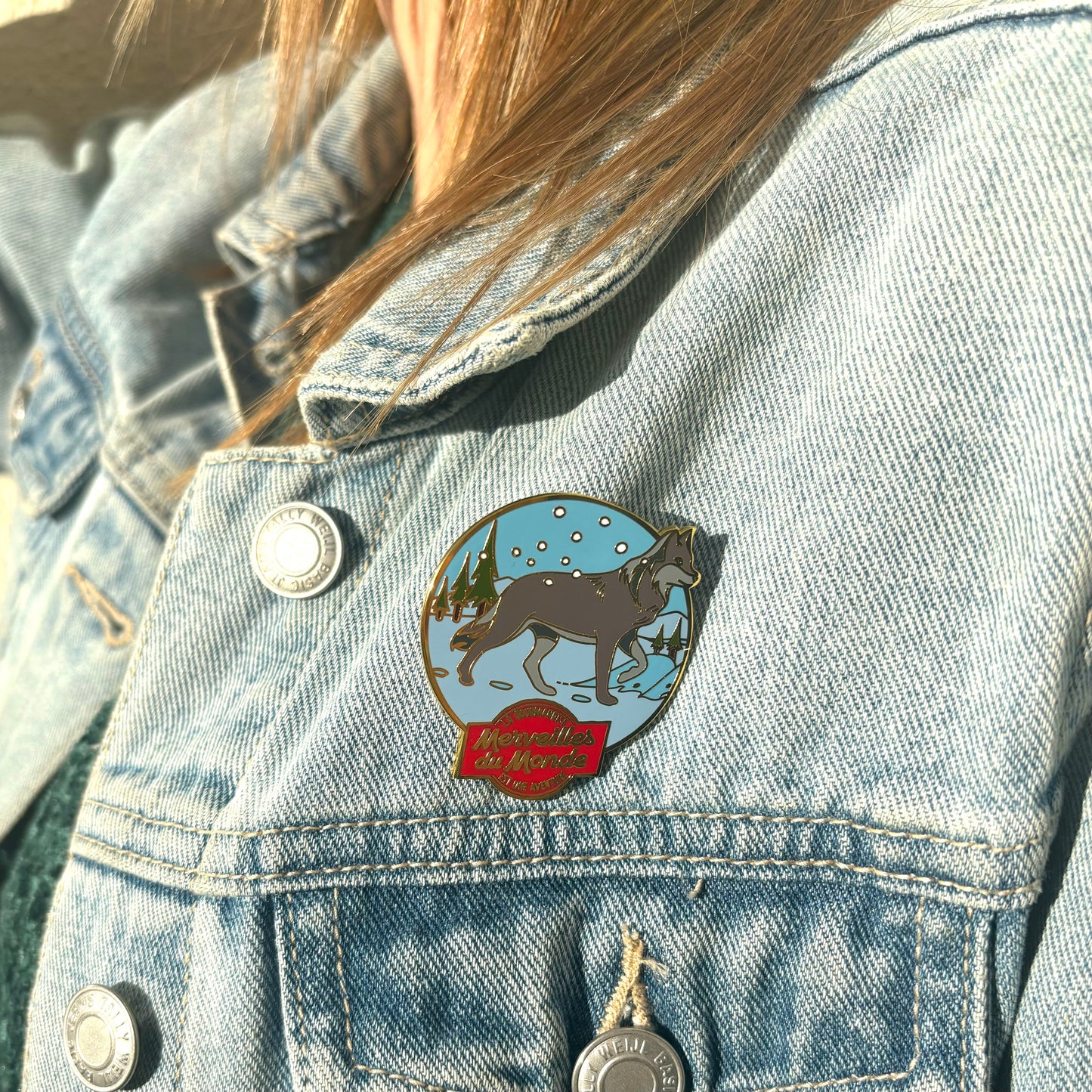 Pin's loup Merveilles du Monde sur veste en jeans.